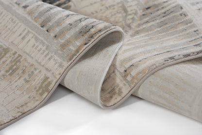 Gray and beige abstract-pattern area rug with soft plush pile; rolled edge reveals light backing.