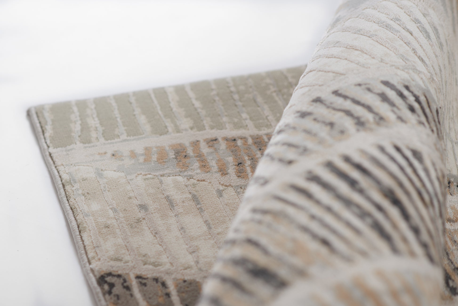 Rolled neutral gray & beige area rug with subtle geometric linear pattern & soft woven texture.