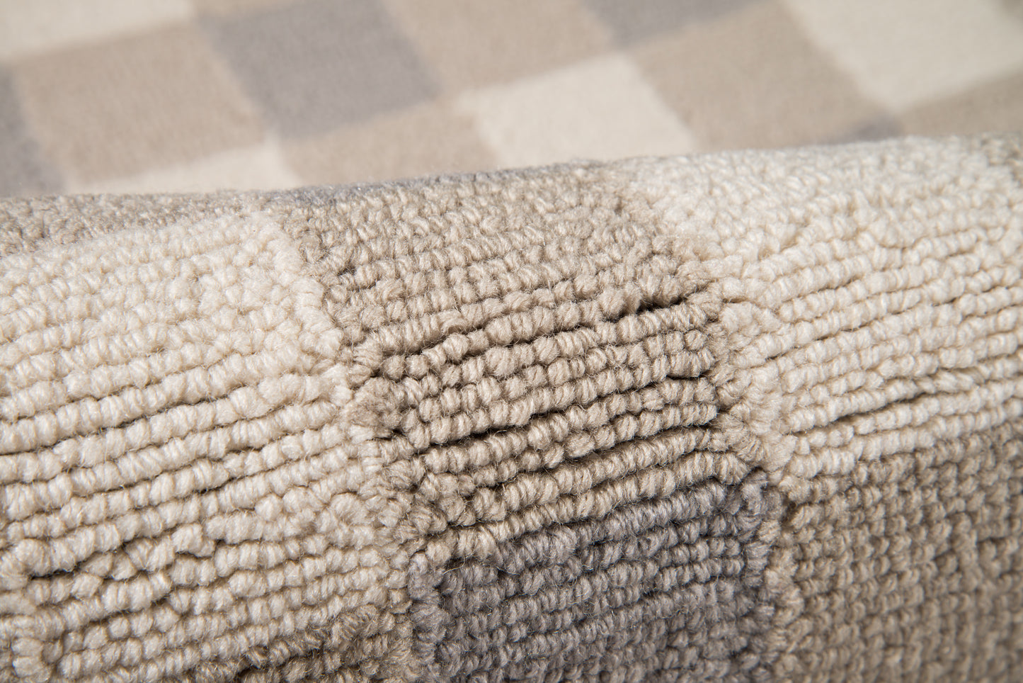 Close-up of a thick, looped-pile rug in grey and beige tones with a plush, textured surface.