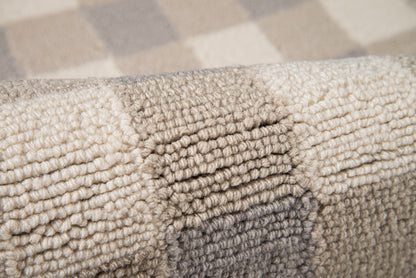 Close-up of a thick, looped-pile rug in grey and beige tones with a plush, textured surface.