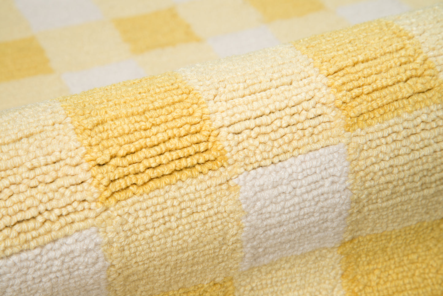 Close-up of yellow and white checkered rug with plush looped texture.