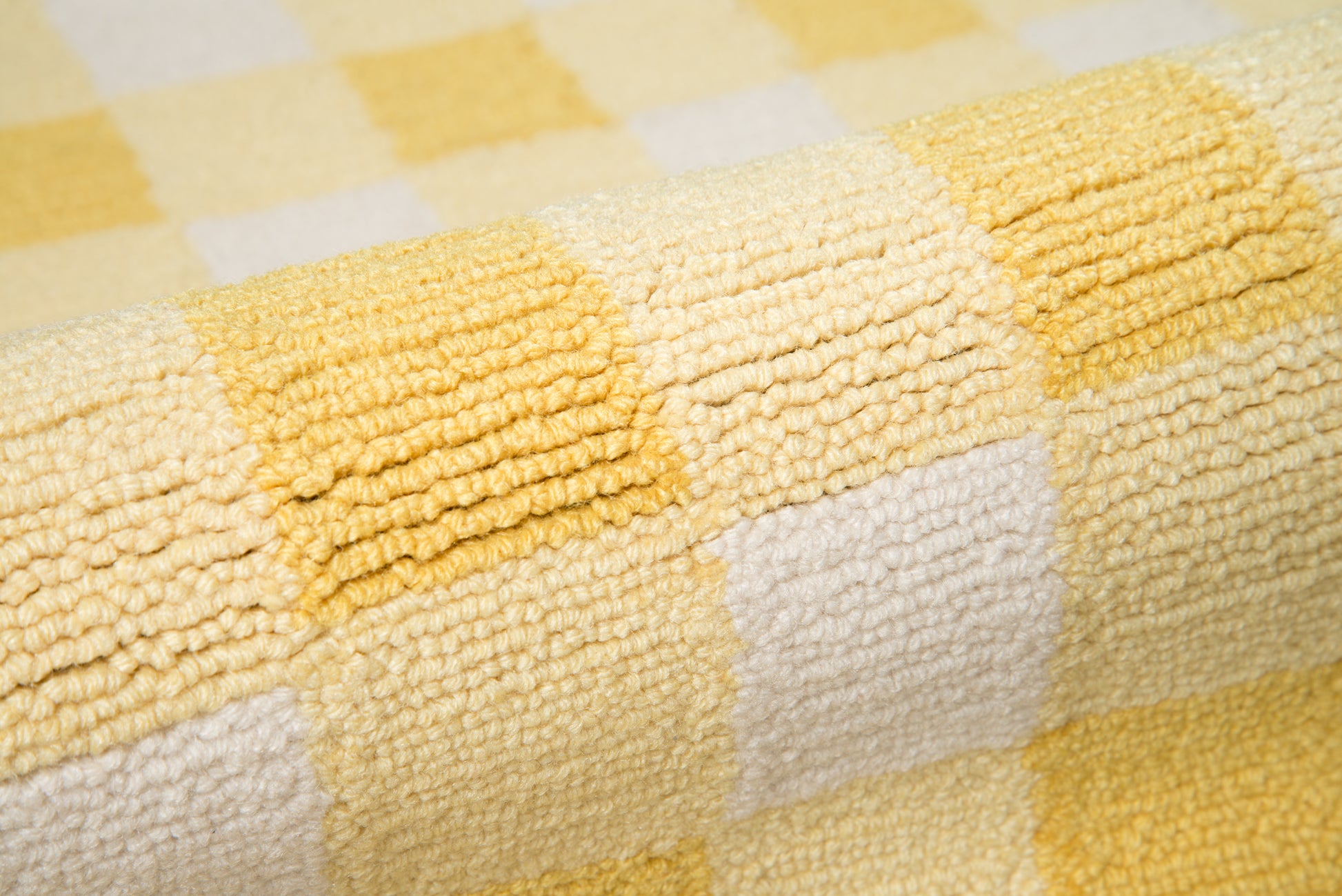 Close-up of yellow and white checkered rug with plush looped texture.