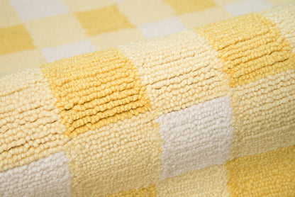 Close-up of yellow and white checkered rug with plush looped texture.