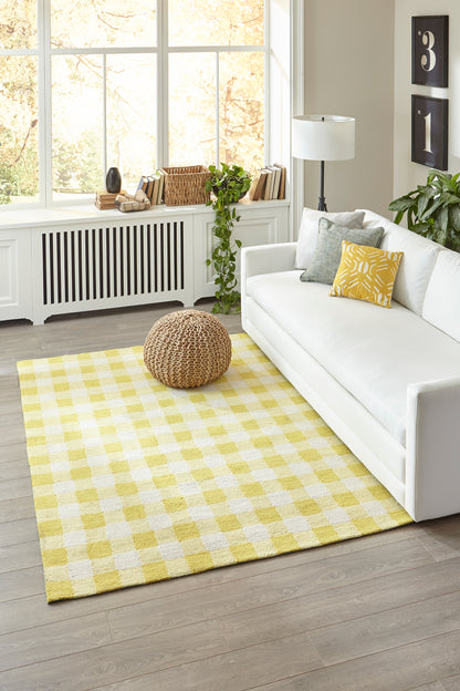 Yellow and white checkered rug in a bright living room with a white sofa and yellow throw pillow.