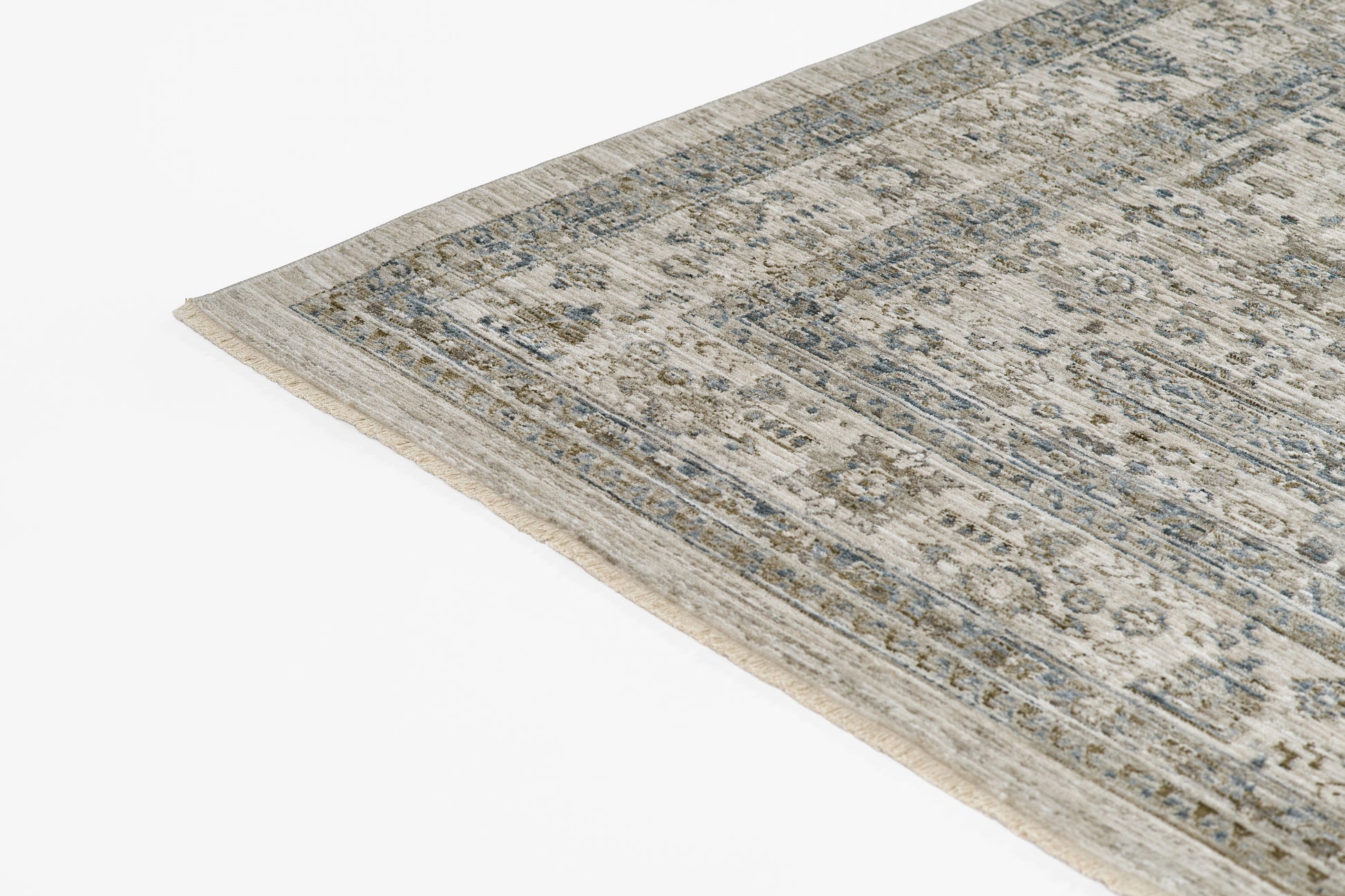 Blue-gray oriental rug with distressed floral medallions and beige border, corner view.