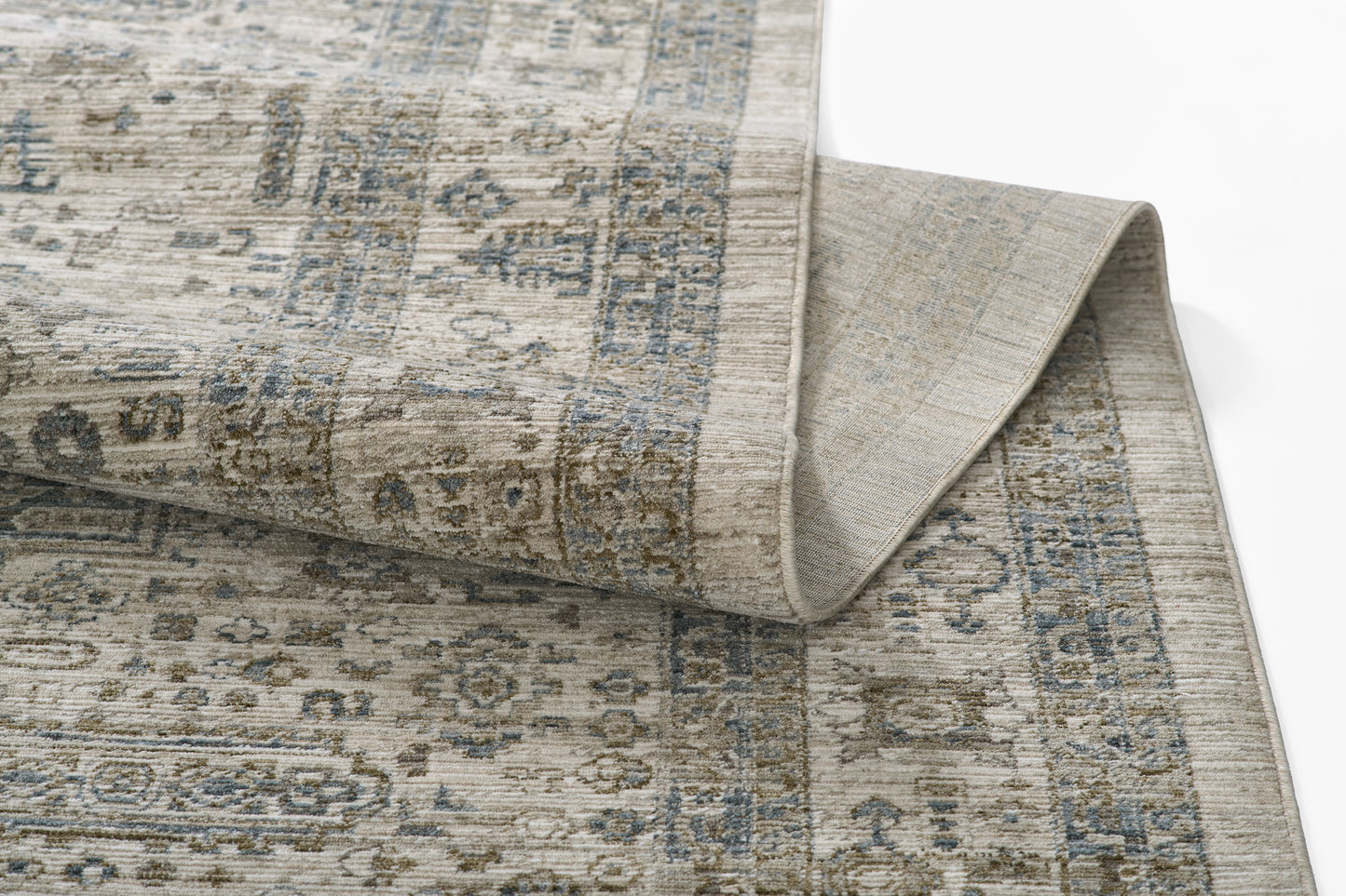Blue-gray and beige oriental rug with vintage floral pattern, folded corner showing underside.