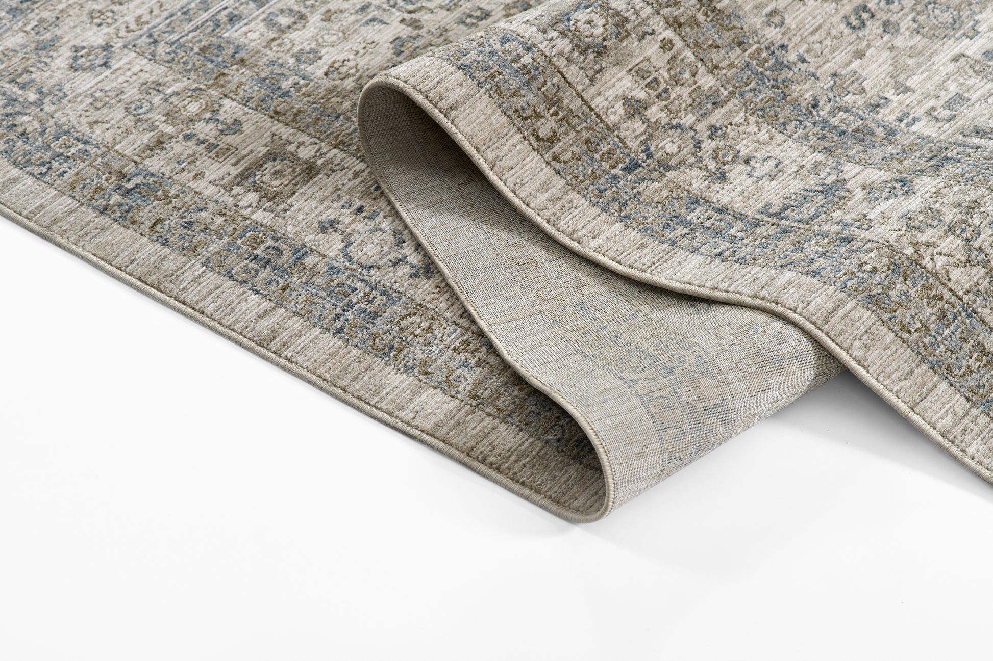 Muted blue-gray Oriental rug with beige distressed pattern; folded edge shows soft backing.