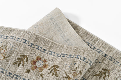 Beige-gray woven runner rug with subtle floral motifs, blue geometric border, folded corner, 3' x 8'.