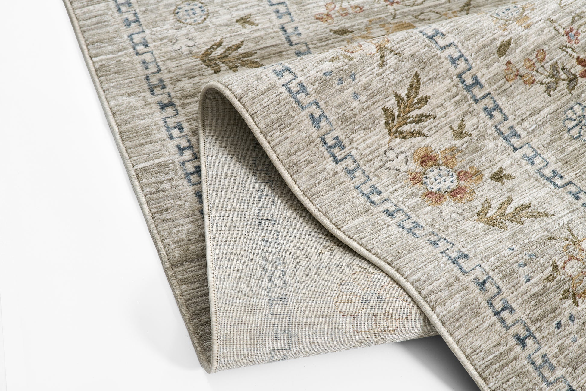 Beige floral area rug with light blue border, woven texture; folded corner reveals pale underside.