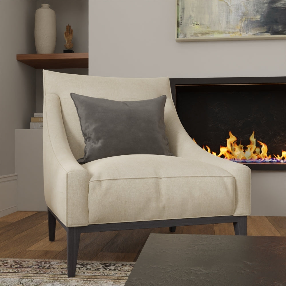 Cream solid fabric armchair with dark wood legs and a gray cushion, in a cozy living room by a lit fireplace.