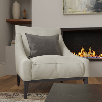 Gray Mercury solid fabric armchair with dark wood legs and a gray cushion in a cozy living room beside a lit fireplace.