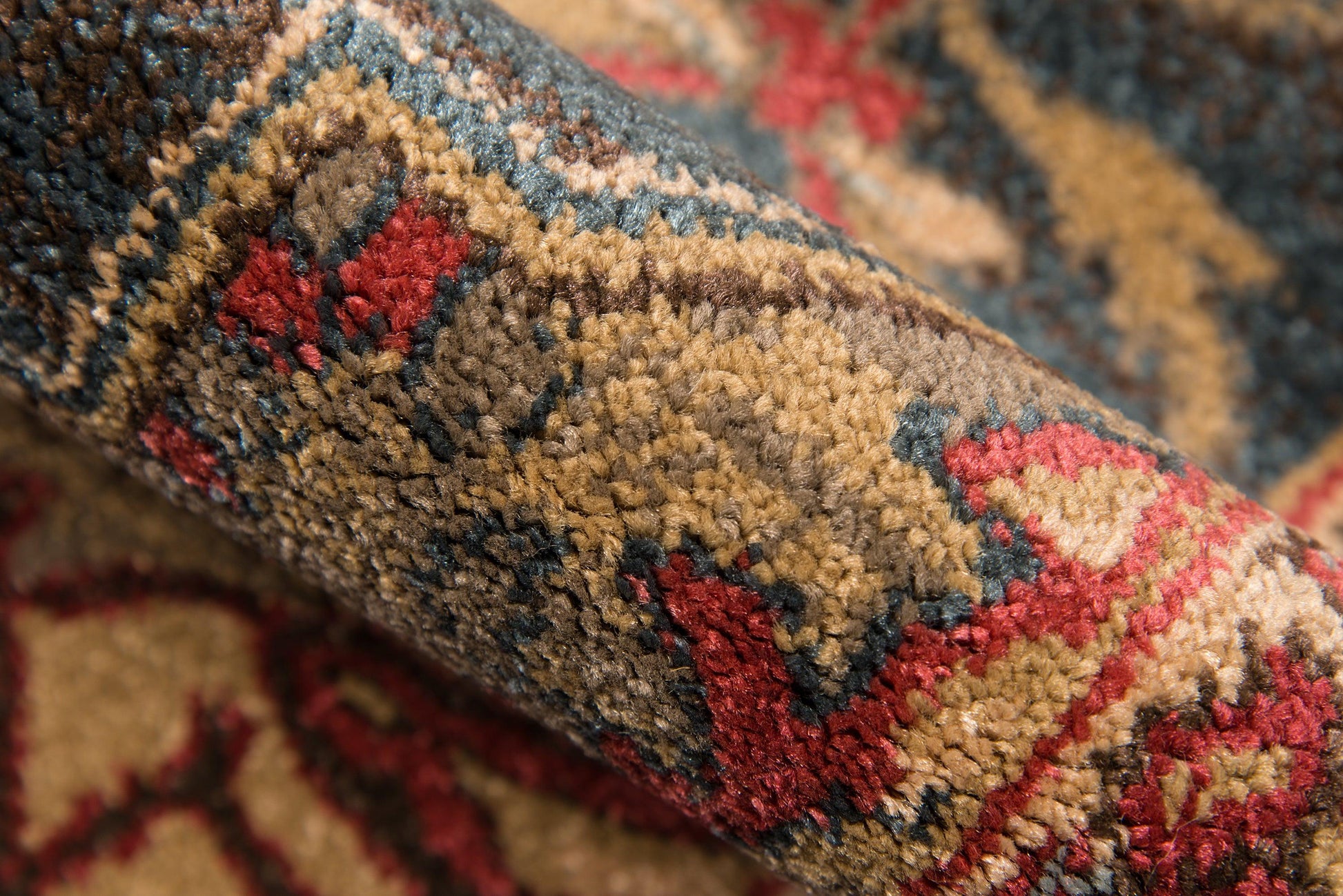 Close-up of a traditional oriental rug with warm brown, red and cream tones, blue accents, and a plush floral pattern.