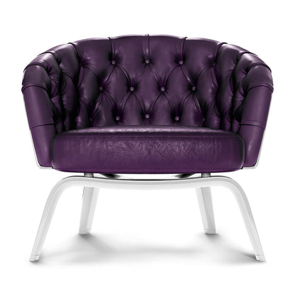 Rich purple tufted leather lounge chair with white metal legs, rounded back & button tufting.
