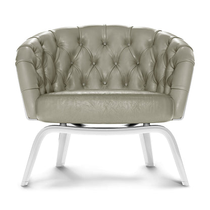 Sage-green tufted leather accent chair with rolled arms and white curved metal legs.