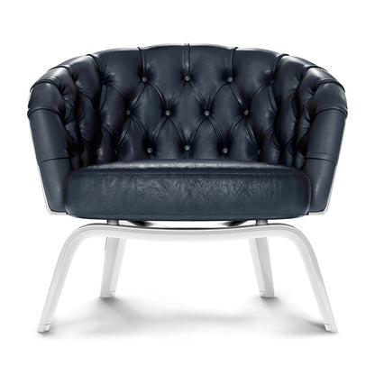 Navy blue tufted leather accent chair with curved back and white metal legs.