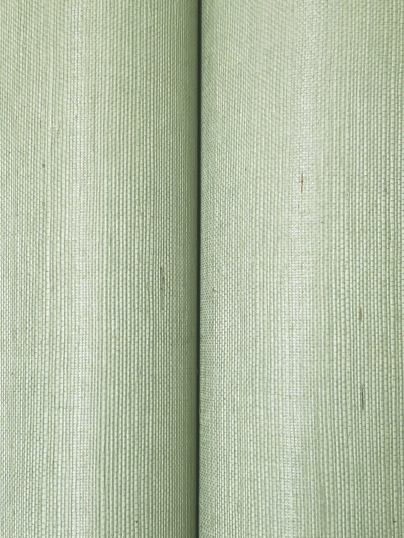 Close-up of soft sage grasscloth wallpaper with vertical ribbed texture.