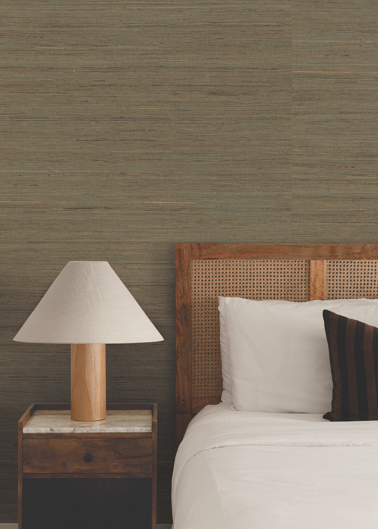 Cozy bedroom with wooden bed frame, white bedding, a brown striped pillow, matching nightstand, and a lampshade lamp