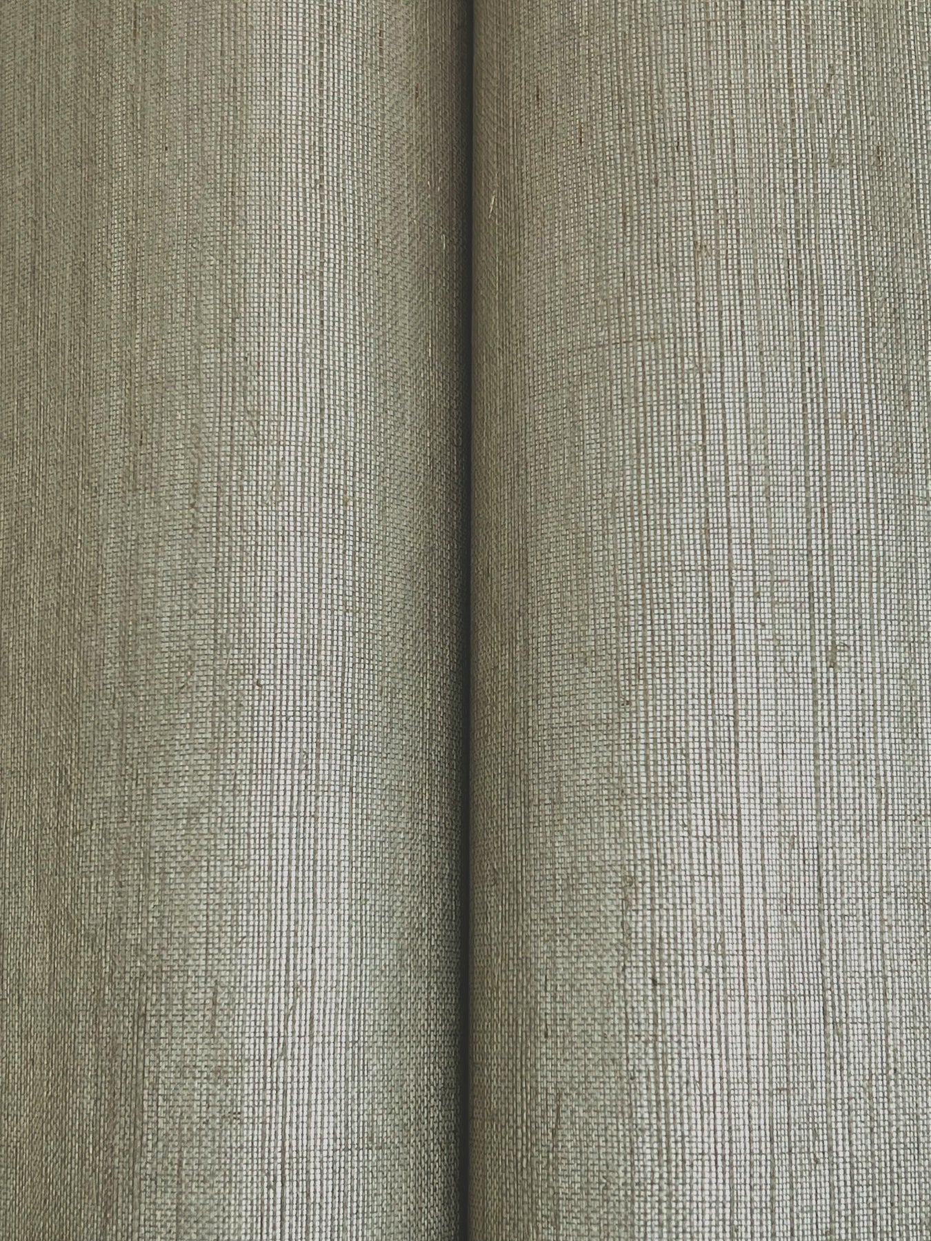 Close-up of two beige-gray wallpaper rolls with a tight vertical weave and textured surface.