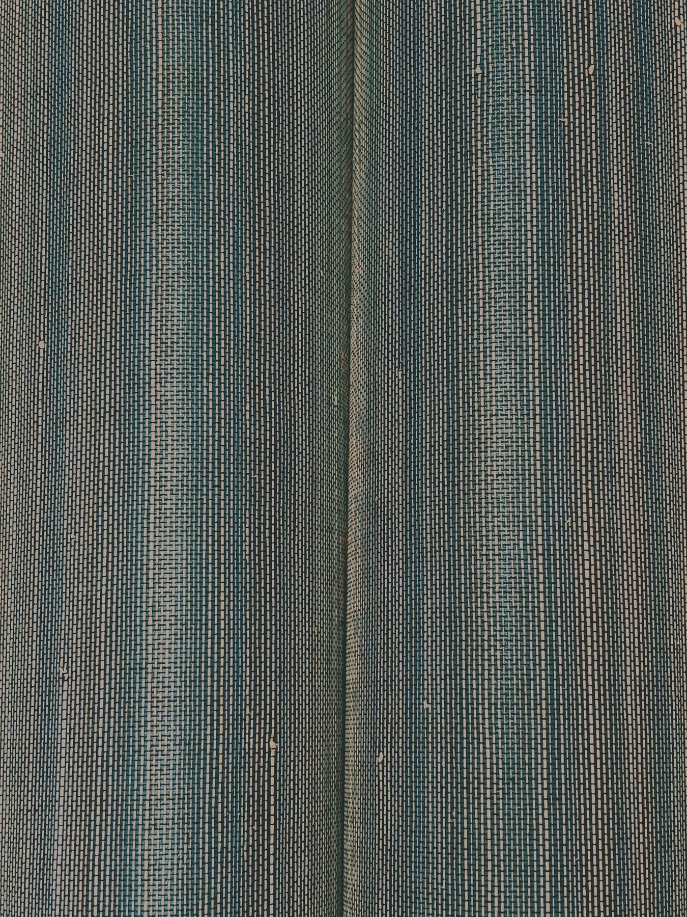 Close-up of teal, gray and blue striped wallpaper with a woven grasscloth texture.
