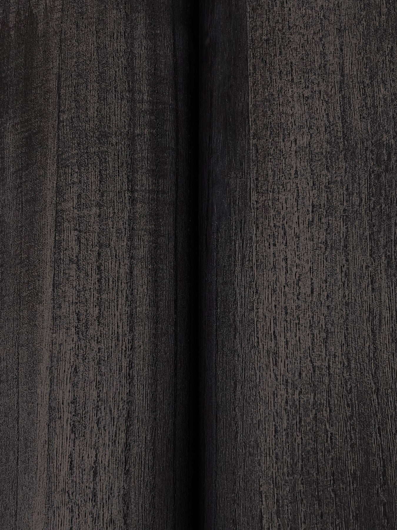 Close-up of dark charcoal wood-grain wallpaper with a central vertical seam; panel-style veneer finish.