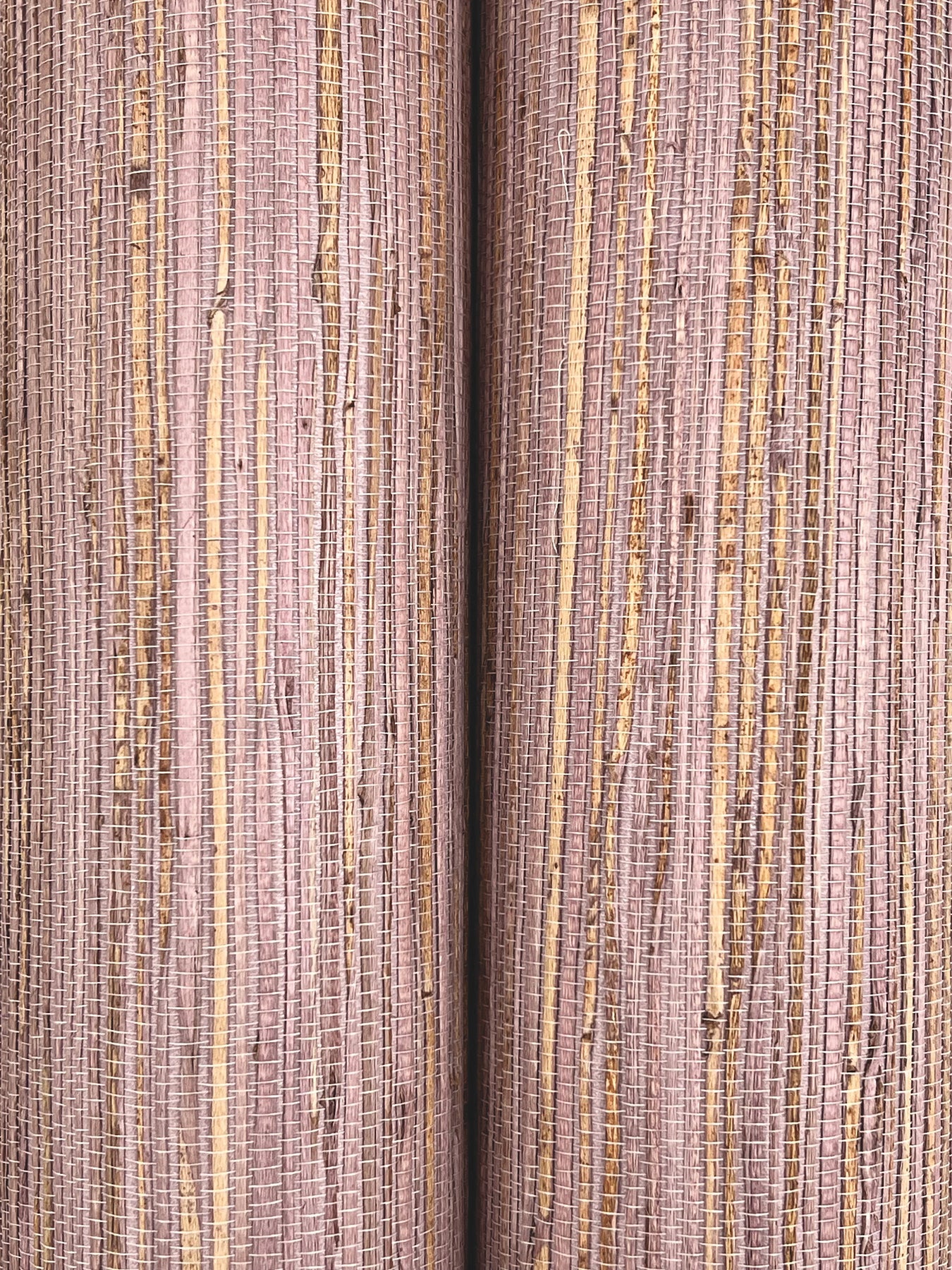 Close-up of mauve woven fabric with slim gold metallic vertical stripes; two fabric rolls side by side.
