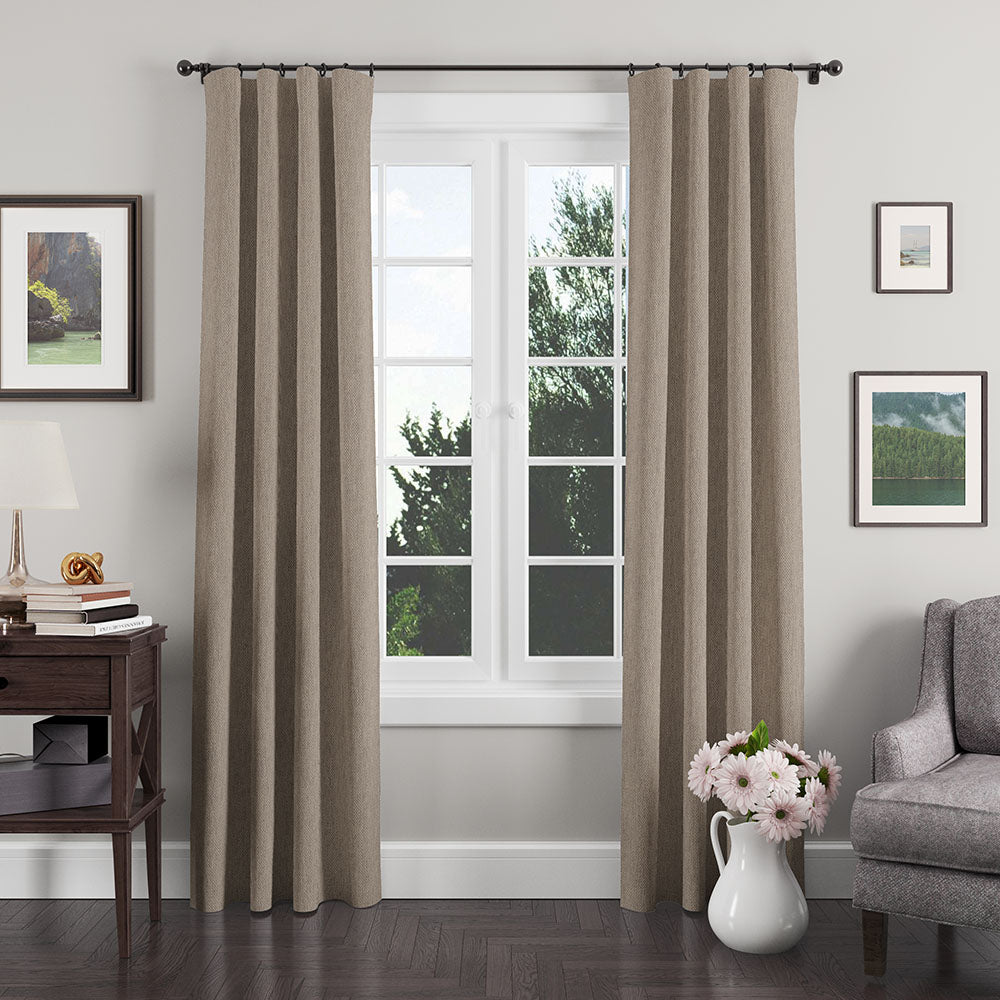Taupe textured grommet curtains, floor-length on a black rod, in a light-gray living room with a white-framed window.