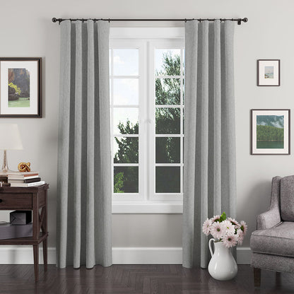 Grey textured floor-length curtains on a black rod, framing a white-framed window in a modern living room.