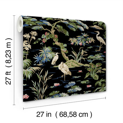 Wallpaper roll with a black background, featuring an Asian garden motif of cranes, bamboo, lotus and lush foliage in greens and pastels.