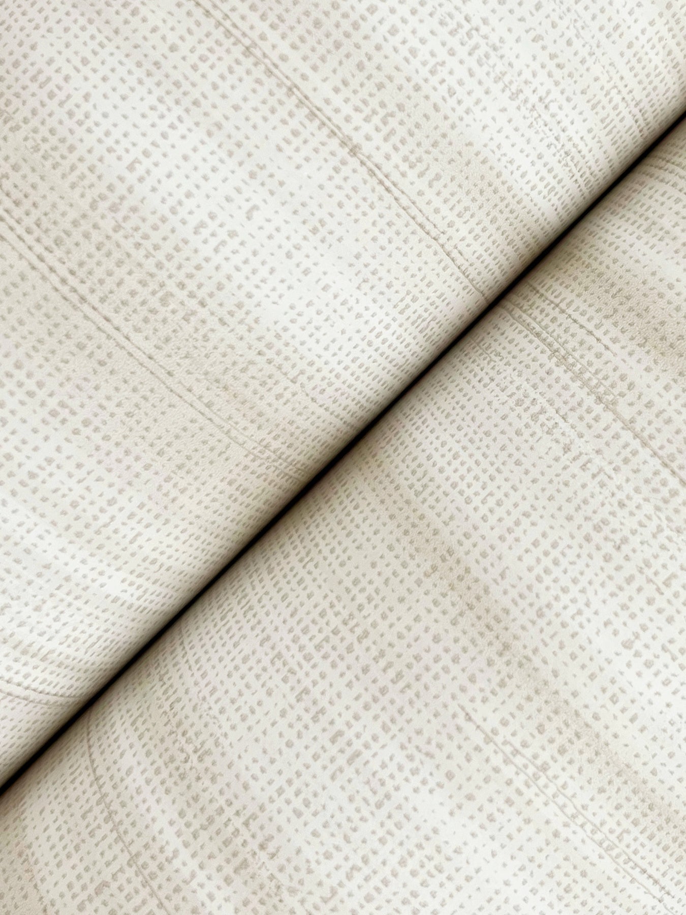 White brushed linen wallpaper with a subtle dotted grid pattern, folded along a diagonal seam.