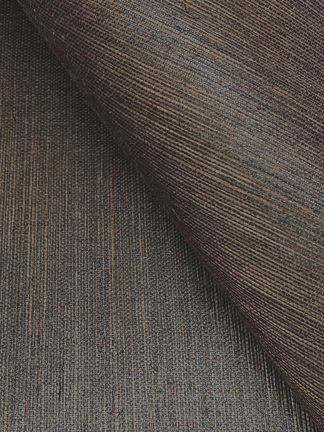 Close-up of brown woven grasscloth wallpaper with subtle vertical stripes and textured surface.