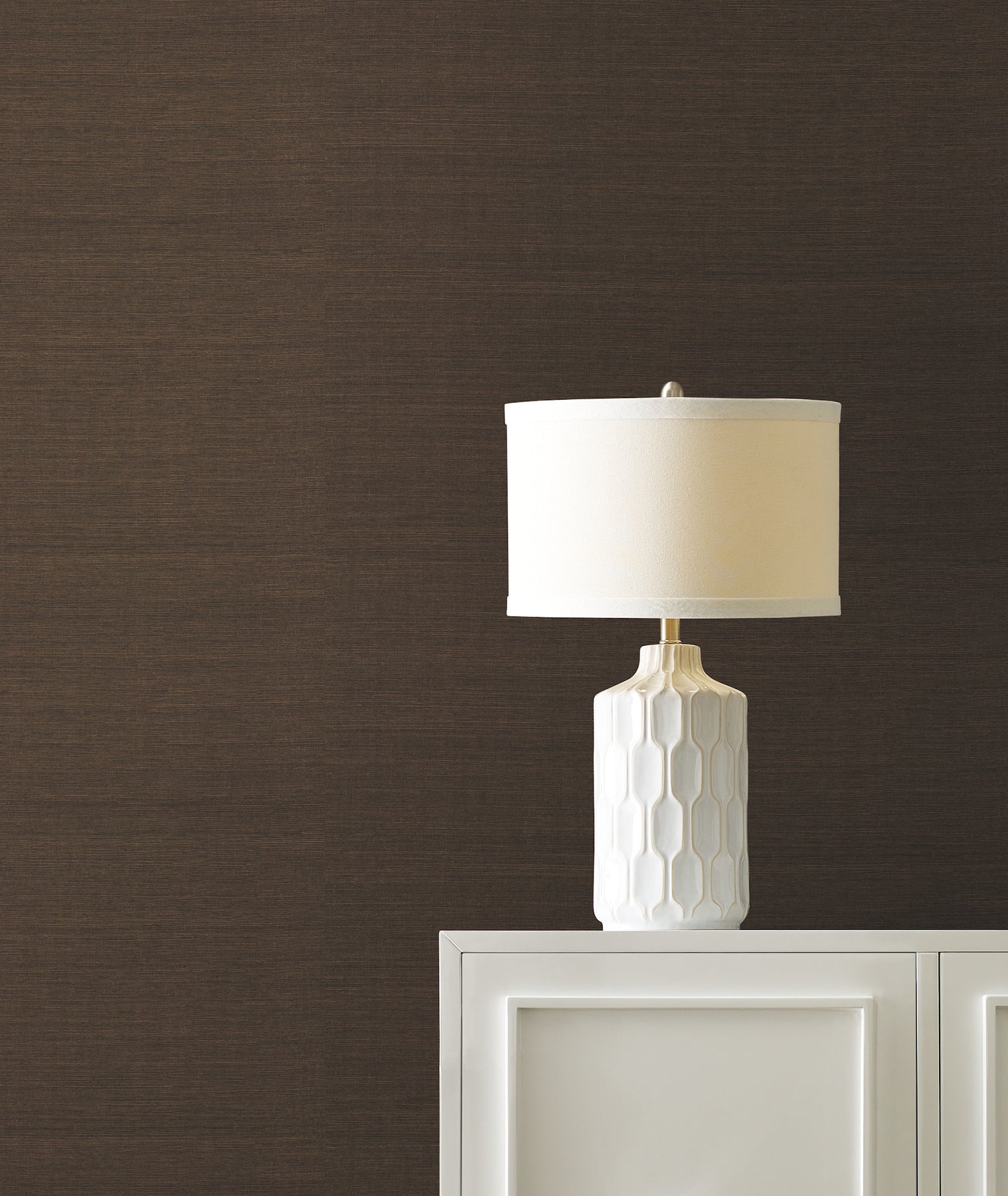 Cream and walnut brown grasscloth wallpaper on a wall behind a white cabinet.