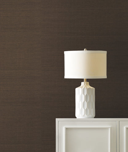 Cream and walnut brown grasscloth wallpaper on a wall behind a white cabinet.