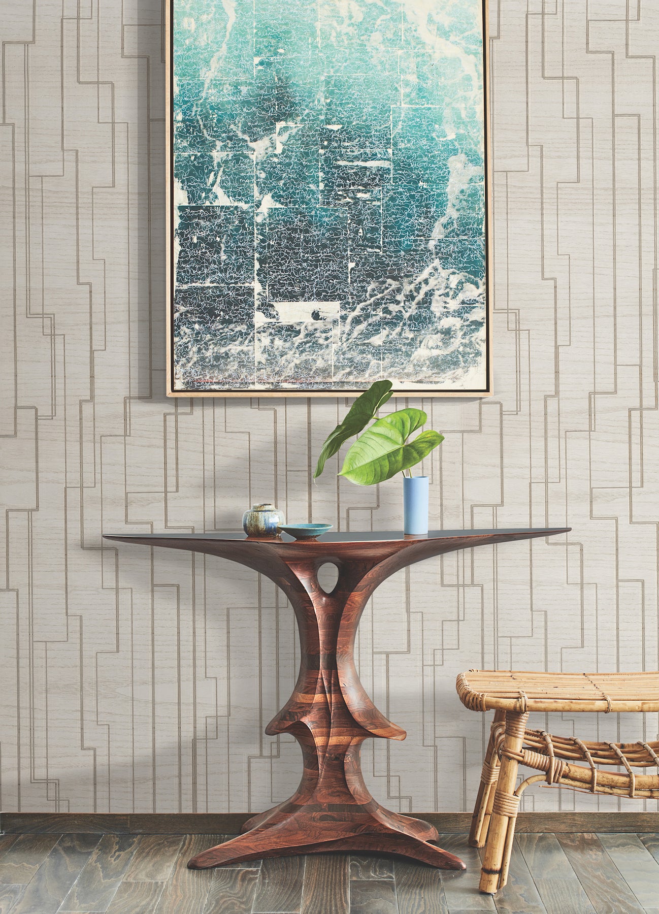 Mid-century wooden pedestal table with curved legs, teal abstract art, potted plant in blue vase, rattan bench nearby.