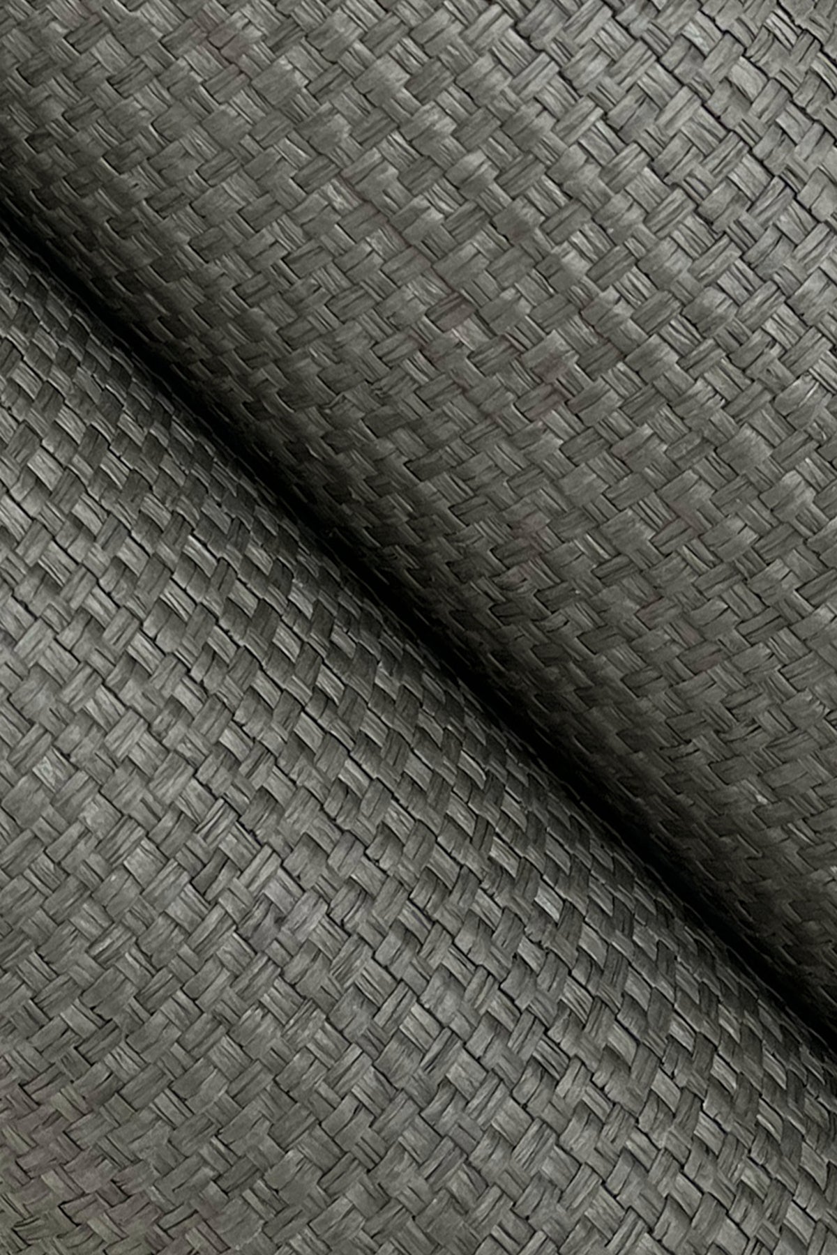Close-up of green grasscloth wallpaper with a woven texture; rolled edge visible.