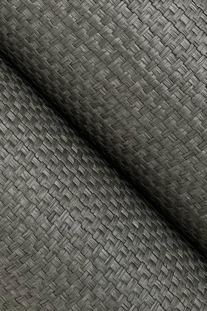 Close-up of green grasscloth wallpaper with a woven texture; rolled edge visible.