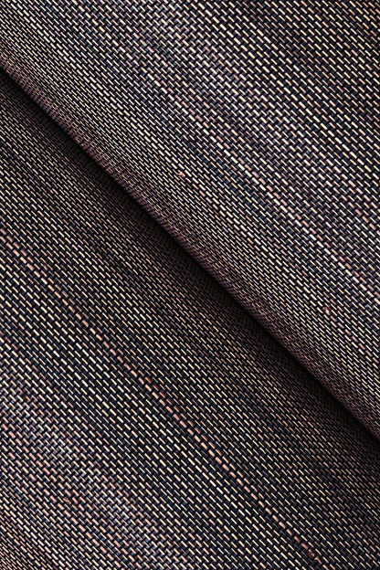 Close-up of grasscloth wallpaper texture in black with multicolor flecks and a diagonal fold.
