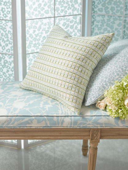 Pastel blue patterned bench cushion with a beige grid-pattern throw pillow, light wood carved legs, floral bouquet nearby.