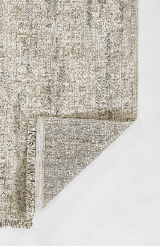 Neutral gray-beige distressed rug with fringed border and soft textured weave; corner folded to reveal underside.