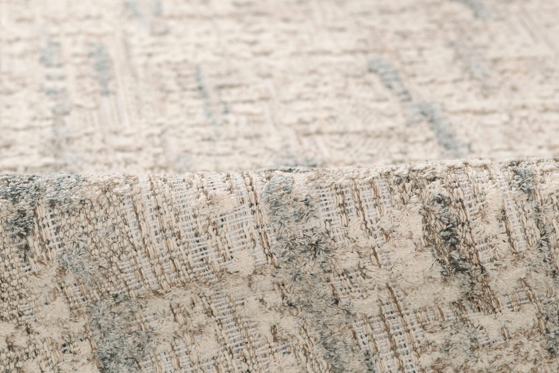 Close-up of a gray and beige distressed woven rug with soft textured pile.