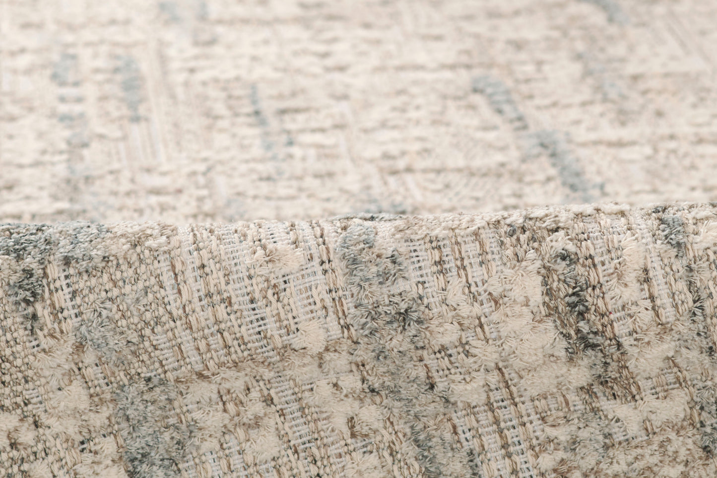 Grey and beige textured area rug with an abstract pattern and folded edge.