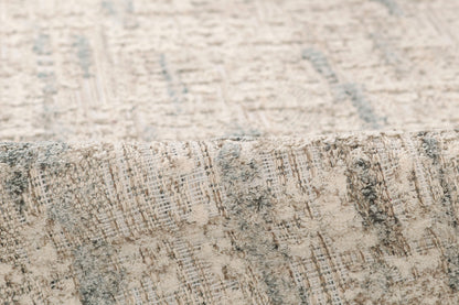 Grey and beige textured area rug with an abstract pattern and folded edge.