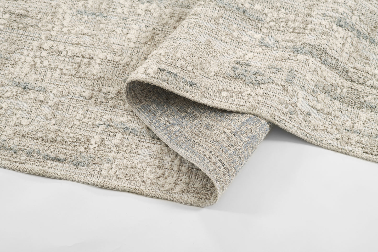 Gray and beige textured woven rug with a distressed pattern and folded edge.