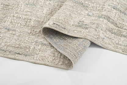 Gray and beige textured woven rug with a distressed pattern and folded edge.