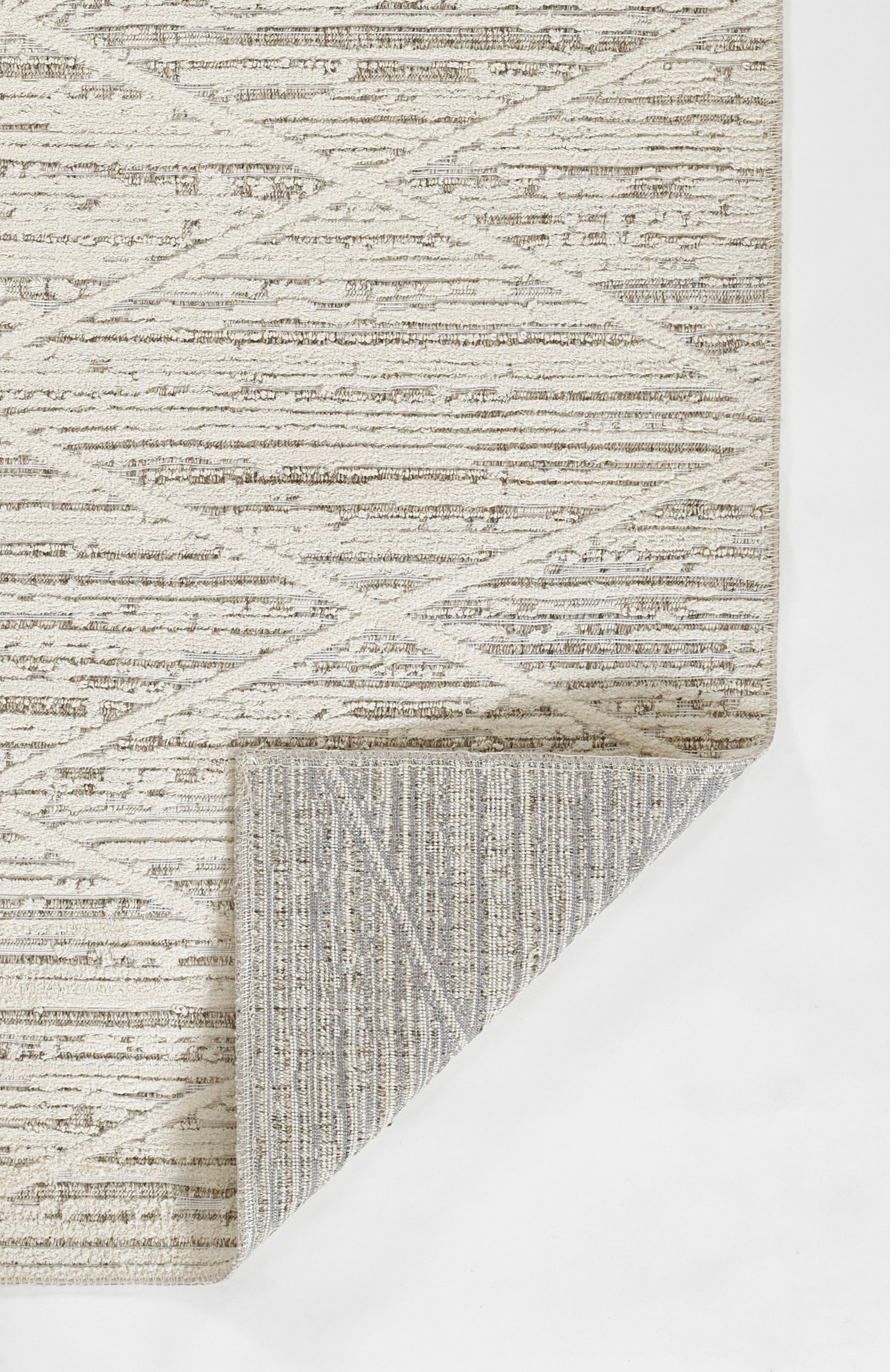 Beige geometric area rug with crisscross diamond pattern; folded corner reveals striped underside.