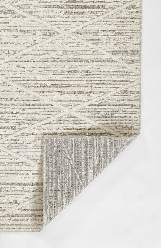 Beige geometric area rug with crisscross diamond pattern; folded corner reveals striped underside.