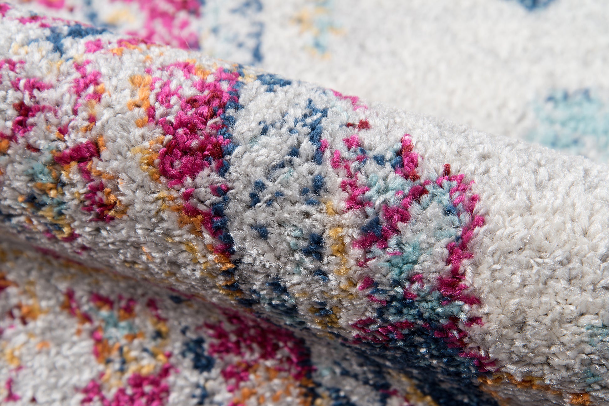 Colorful shaggy area rug with pink, blue, teal and yellow accents on a light base; plush tufted pile.