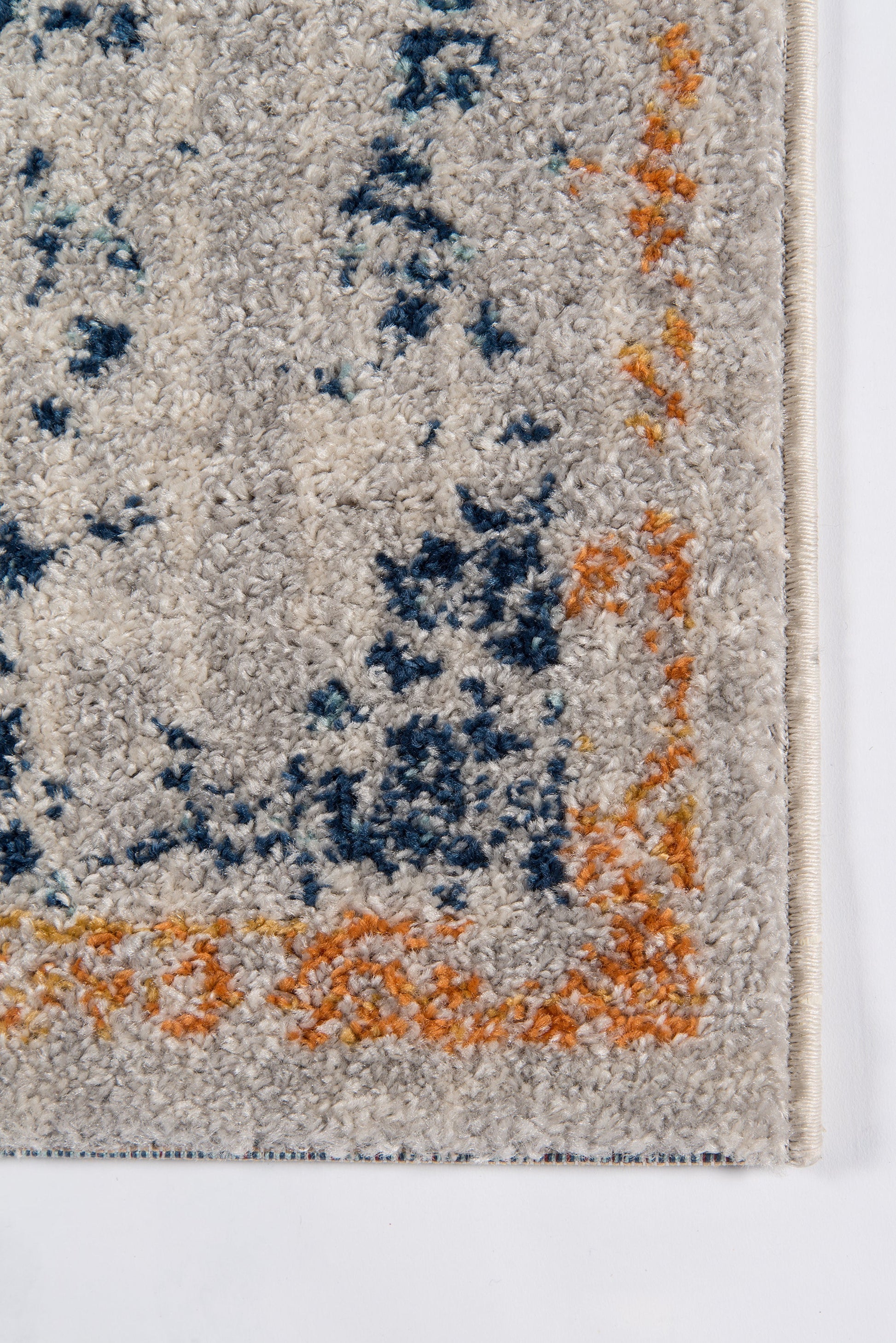 Beige shag rug with blue/teal abstract pattern and orange border; plush textured pile.