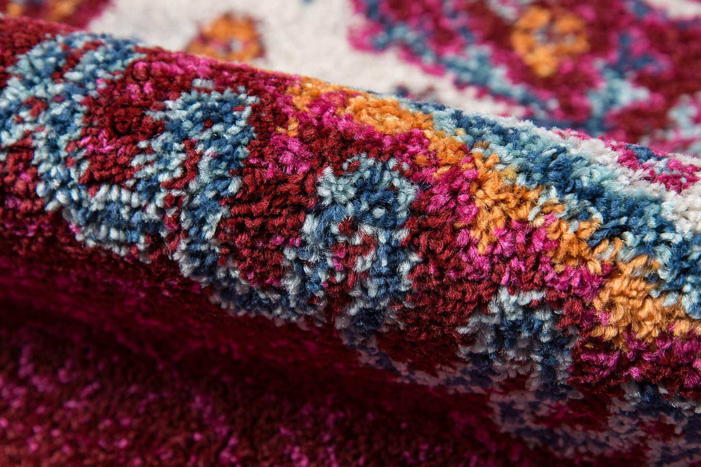 Close-up of a plush multicolor rug with blue, pink, orange and magenta floral pattern and thick pile.