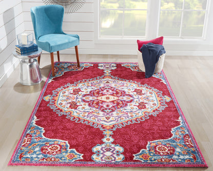 Magenta oriental rug with turquoise and ivory medallion, ornate border, in a bright room with a blue velvet chair.