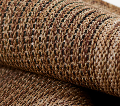 Close-up of natural raffia straw weave in tan and brown with black accents on a textured rug runner